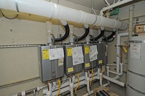 Three tankless water heaters in a multifamily property basement.