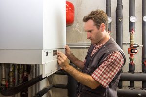 Man adjusting the controls on a commercial boiler.