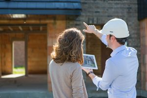 View of a woman and architect on construction site pointing at a house.