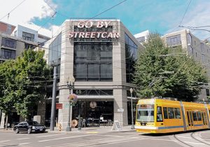 View of the front of the Streetcar Lofts building with a yellow streetcar passing in front.