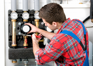 a workman in bright red flannel shirt upgrading a boiler
