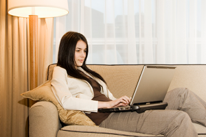 women reclining on couch using a laptop