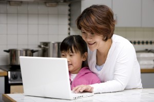 mother helping young daughter on a laptop