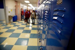 a school hallway lined with lockers and a checker board floor students in the distance